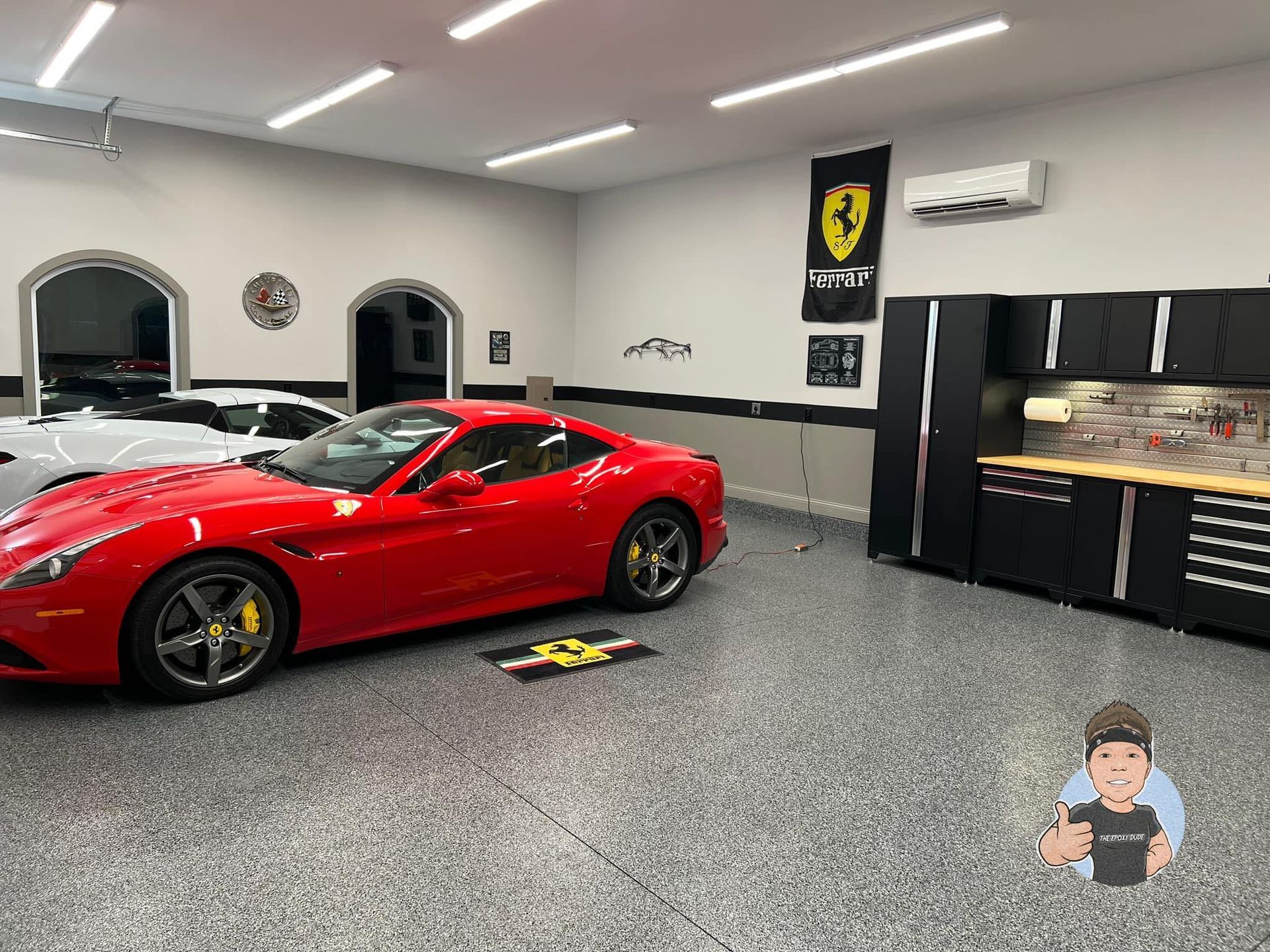 Red Ferrari sports car in a modern garage with black cabinets and a Ferrari flag.