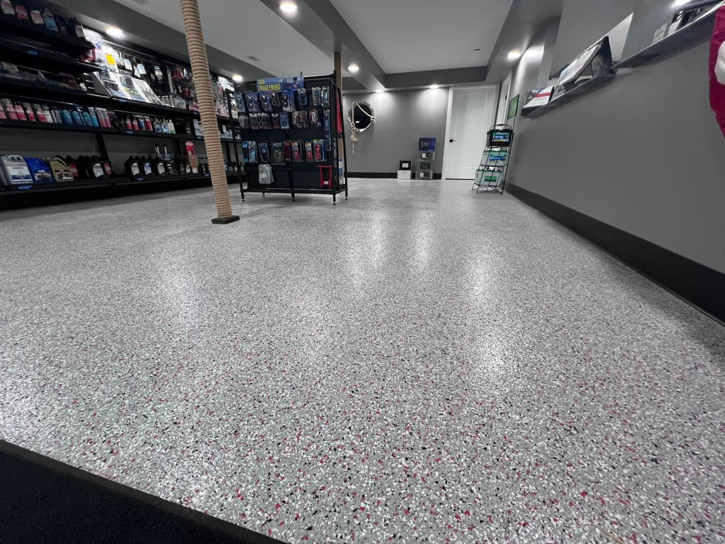 Interior of a store with a speckled floor, shelves, and a counter.
