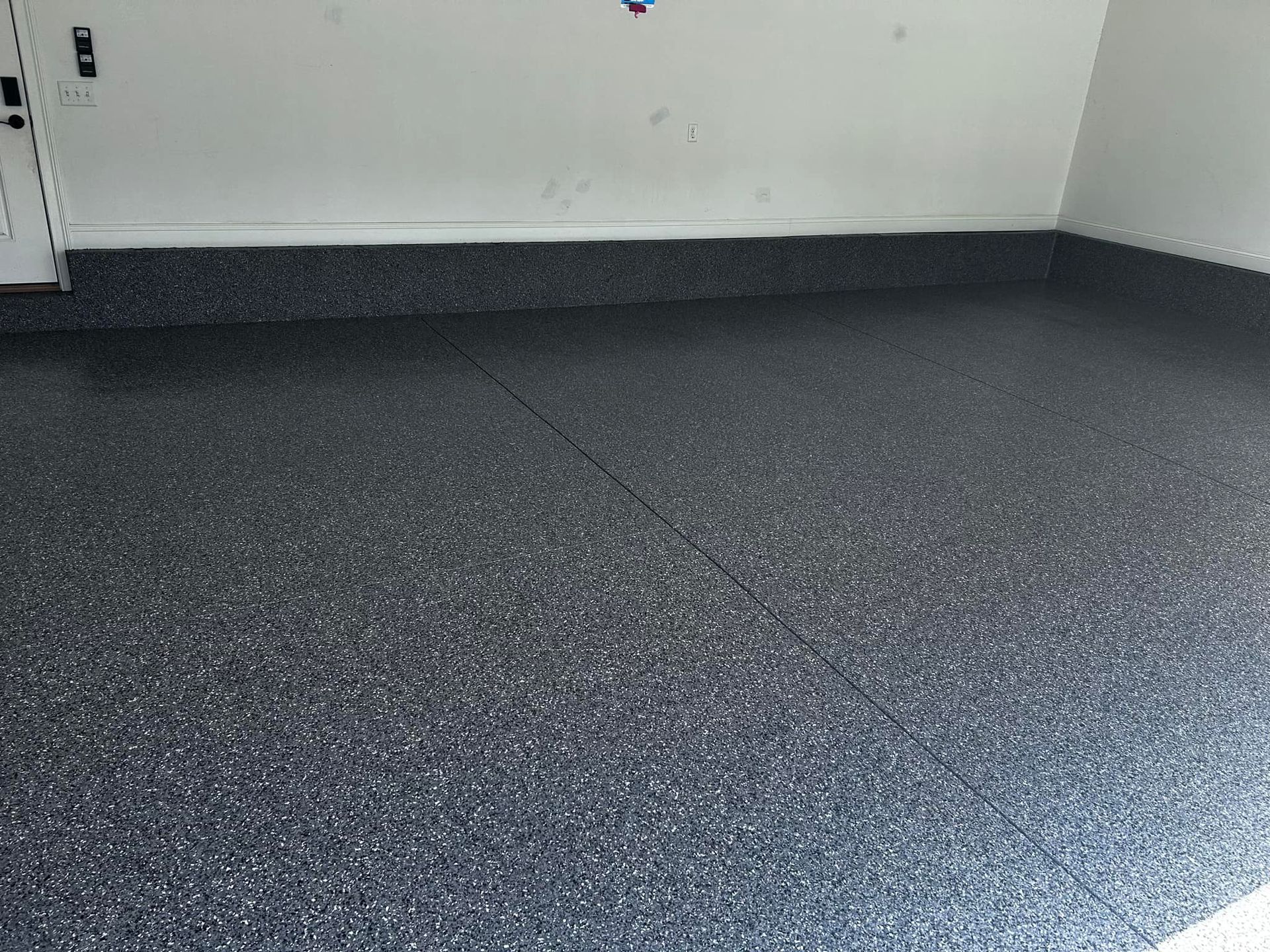 Dark speckled epoxy garage floor against white walls.