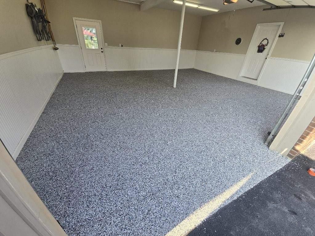Garage with gray speckled floor, white walls, and a white pole.
