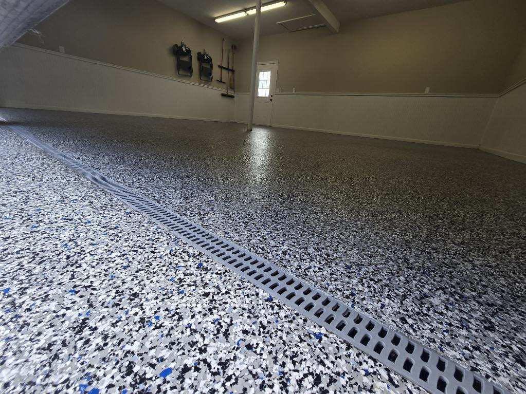 Garage floor with speckled epoxy coating and a linear drain.