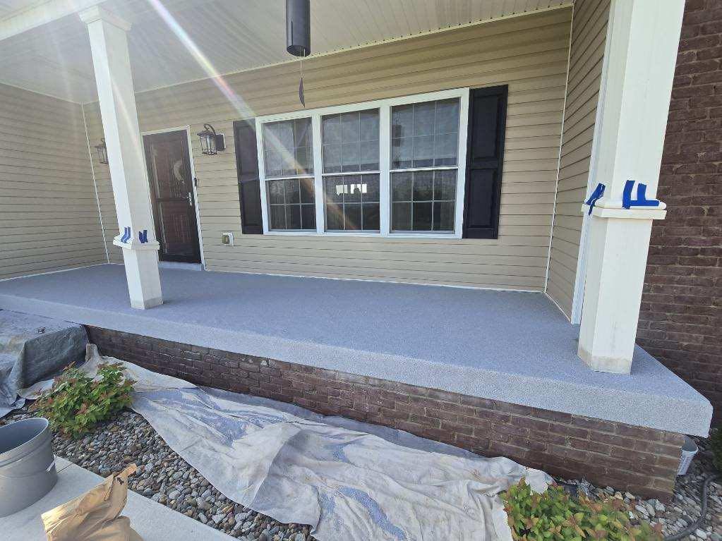 Front porch with newly painted gray concrete floor and white pillars.
