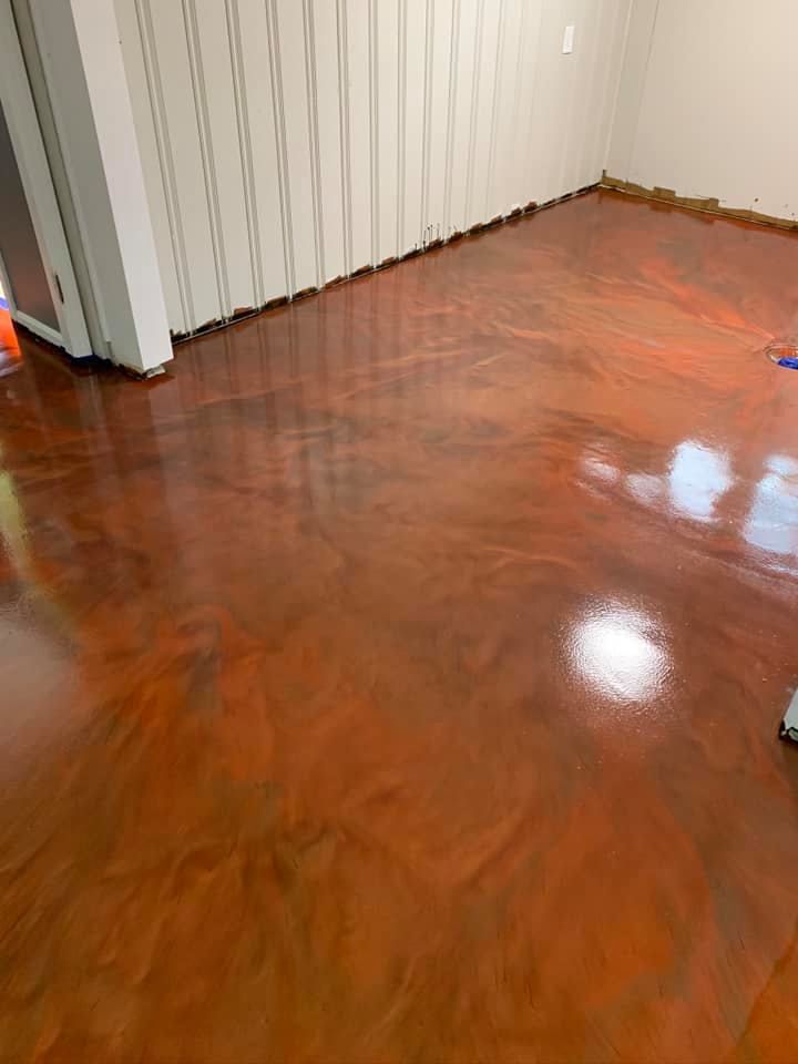 Metallic orange epoxy floor with swirling patterns in a room with white walls.