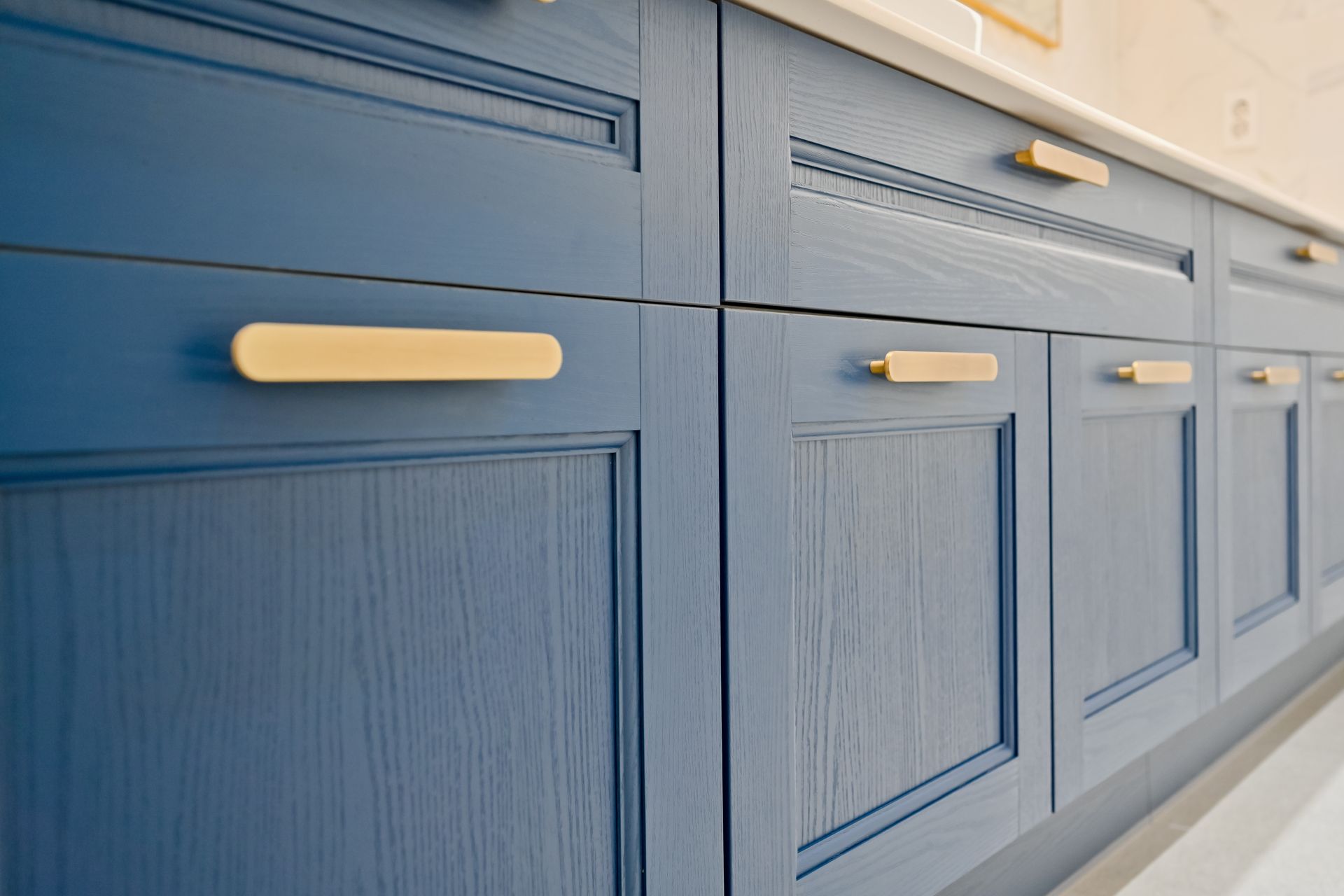 A kitchen with blue cabinets and gold handles.