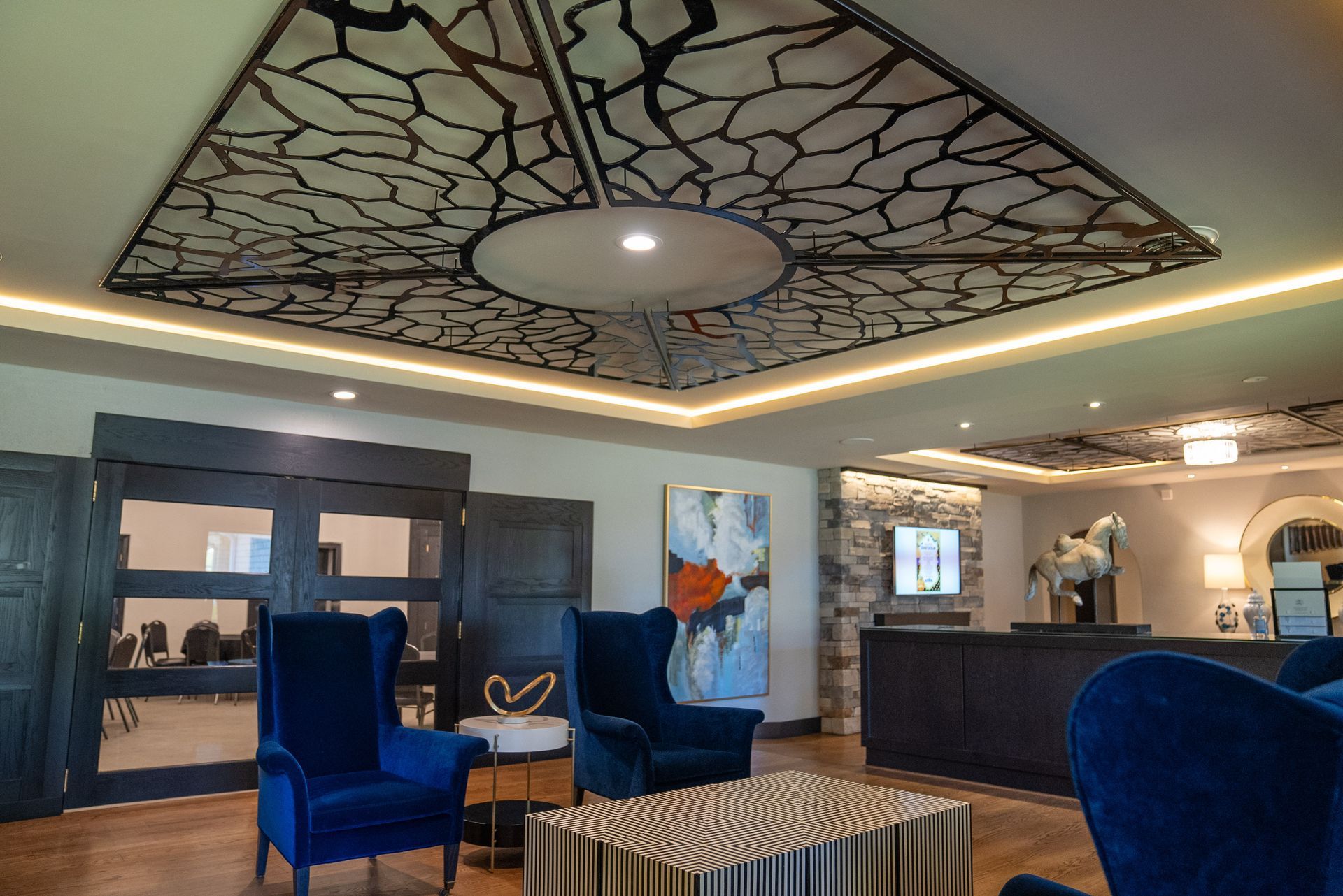 Lobby with blue armchairs, a patterned ceiling, and a reception desk.