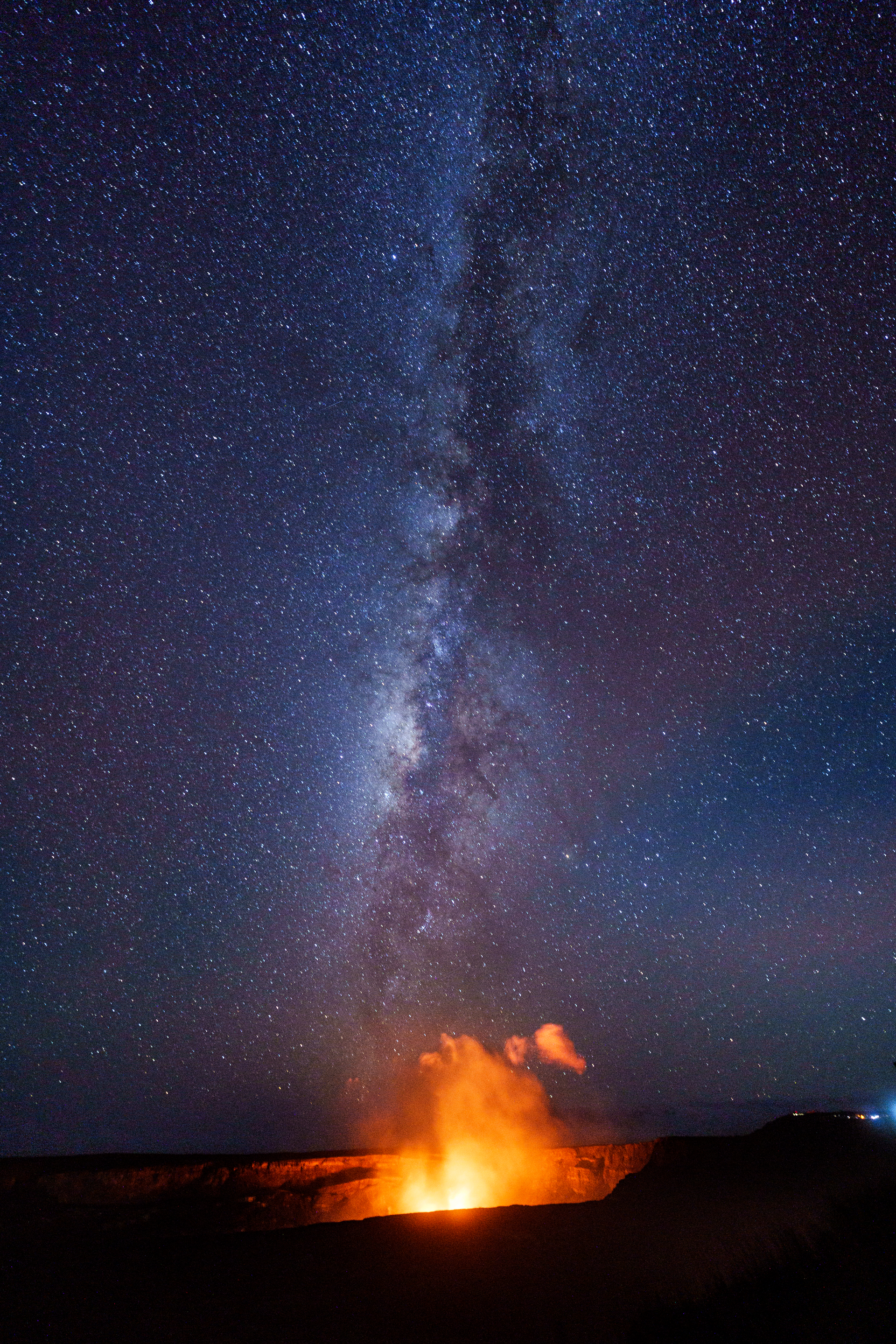 A volcano is erupting under a starry night sky.