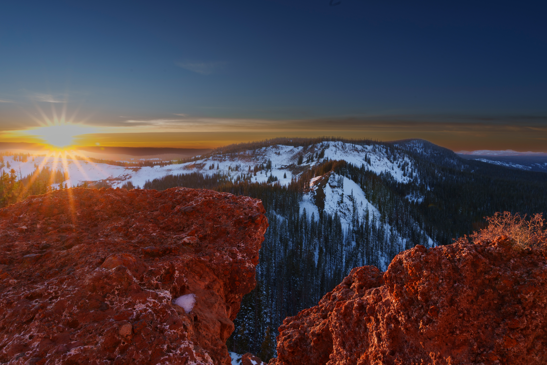 The sun is setting over a snowy mountain range.