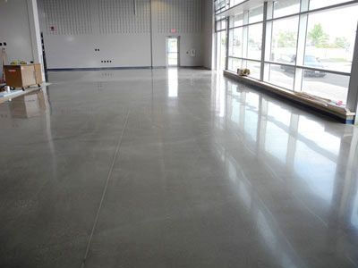 A large empty room with a shiny concrete floor and lots of windows.