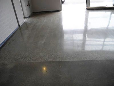 A shiny concrete floor in a room with a door and a window.