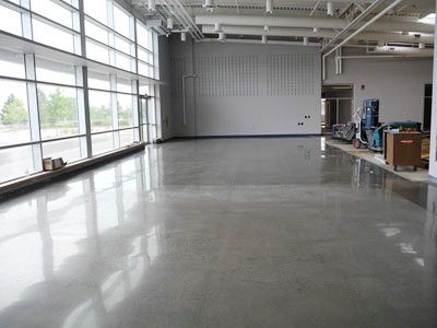 A large empty room with a shiny concrete floor and lots of windows.