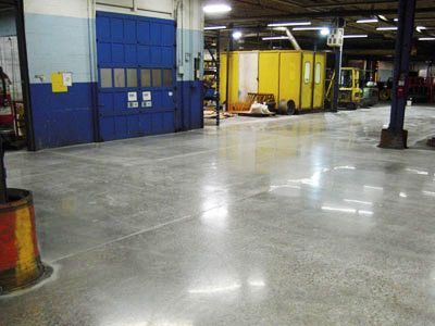 A large warehouse with a shiny concrete floor and a blue door.
