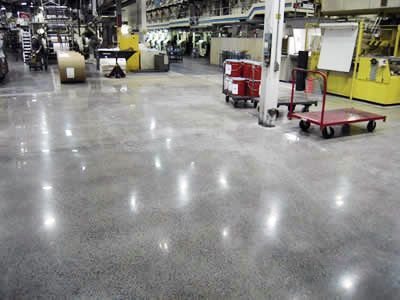 A warehouse with a shiny concrete floor and a red cart.