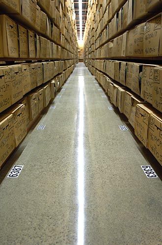 A long hallway in a warehouse filled with lots of boxes.