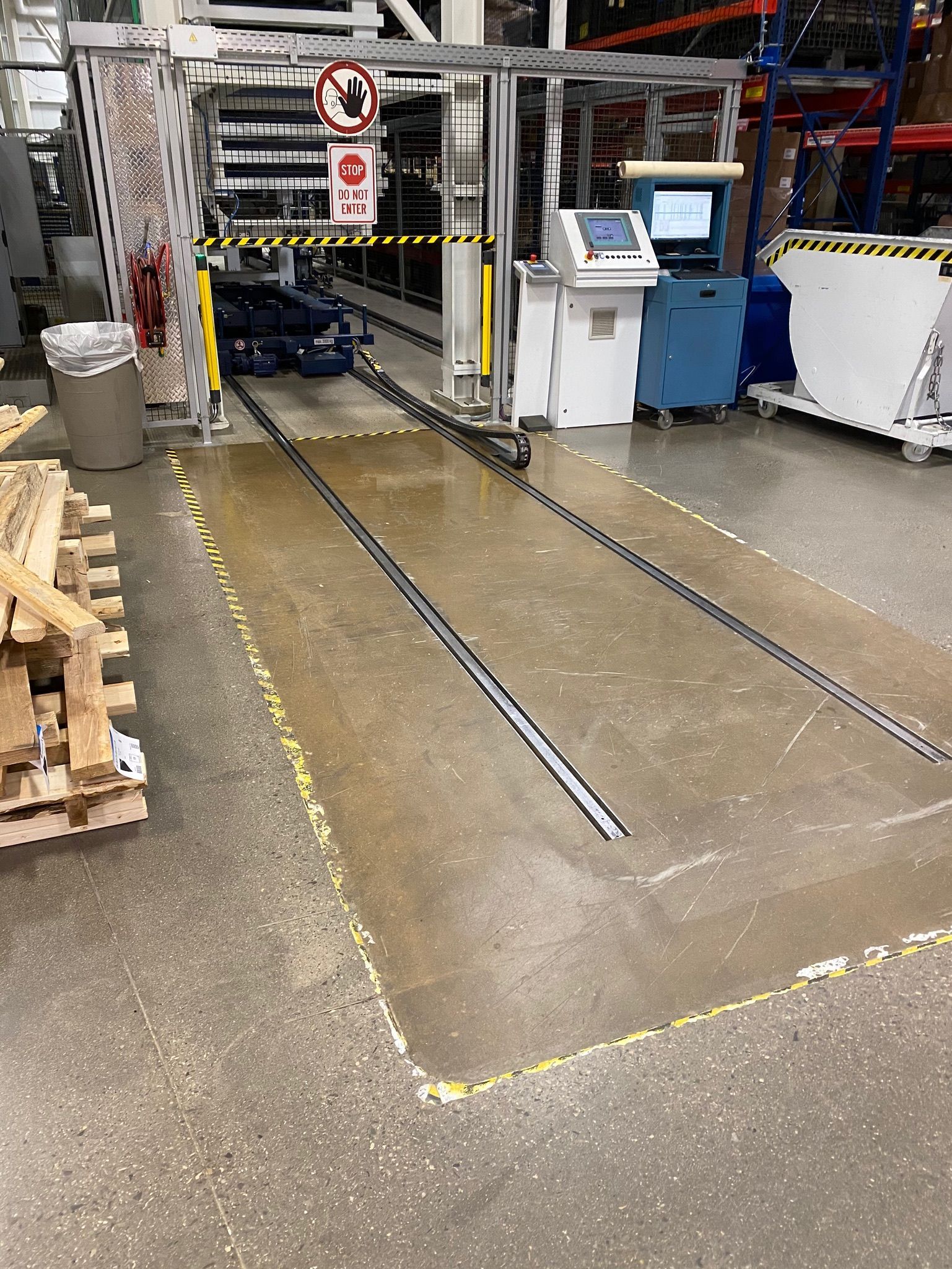 A warehouse with a lot of pallets and a machine on the floor.