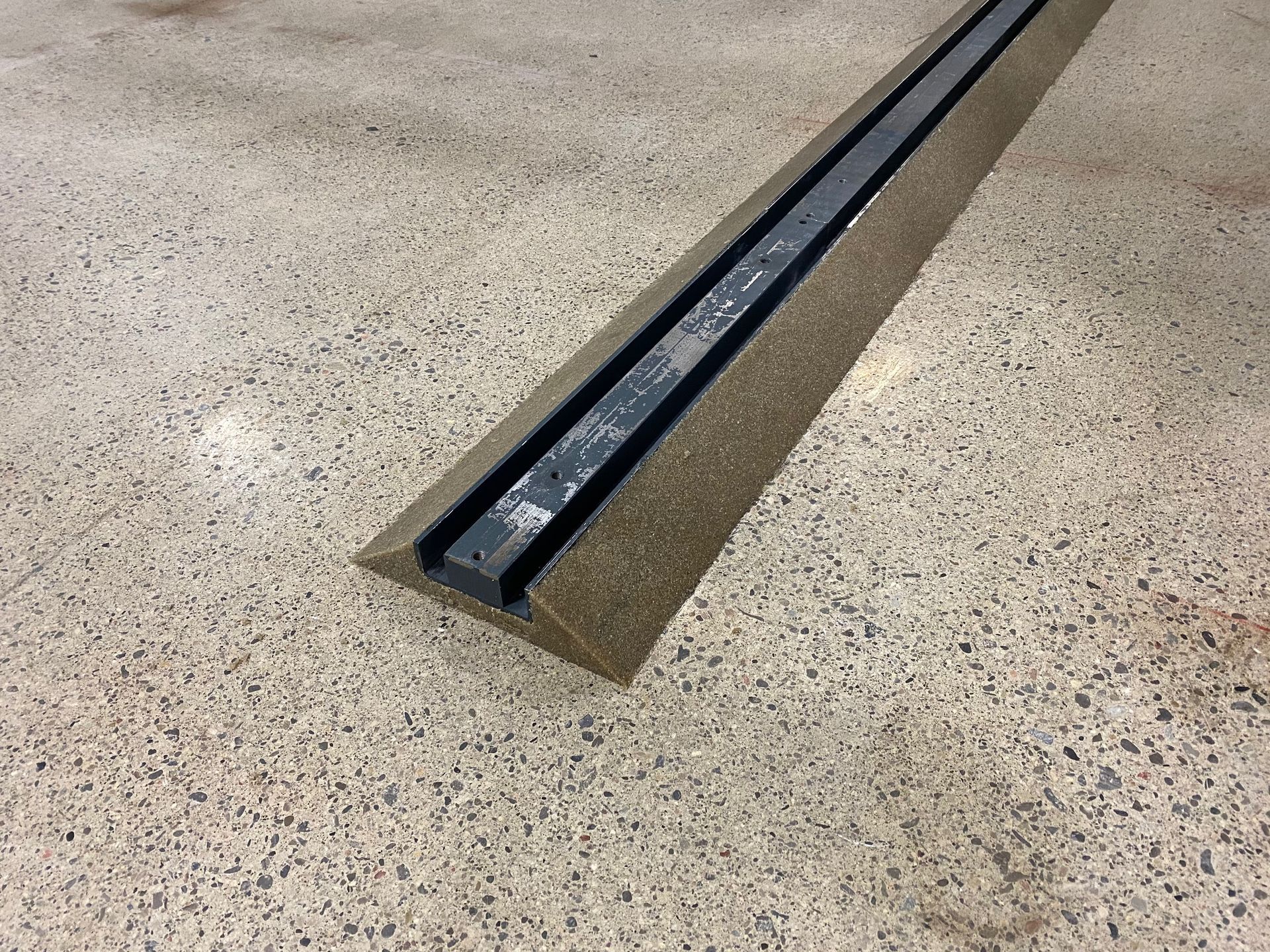 A piece of metal is sitting on a concrete floor.