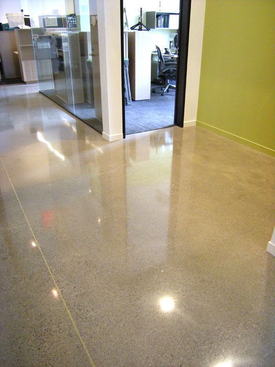 A shiny concrete floor in an office with a green wall