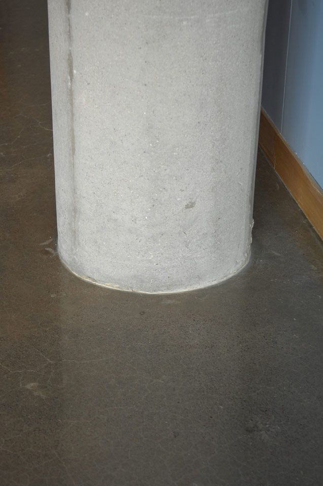 A concrete column is sitting on a concrete floor next to a wall.