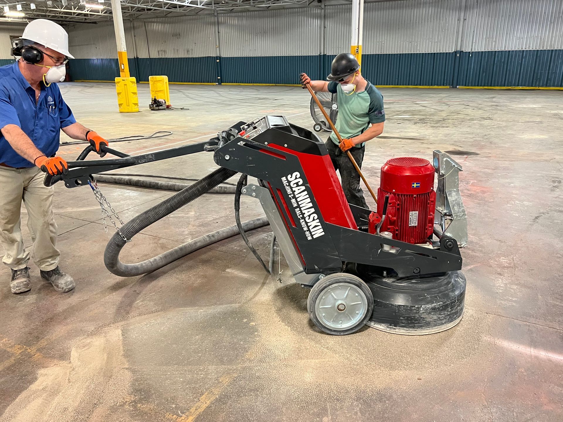 Two men are working on a machine in a warehouse.