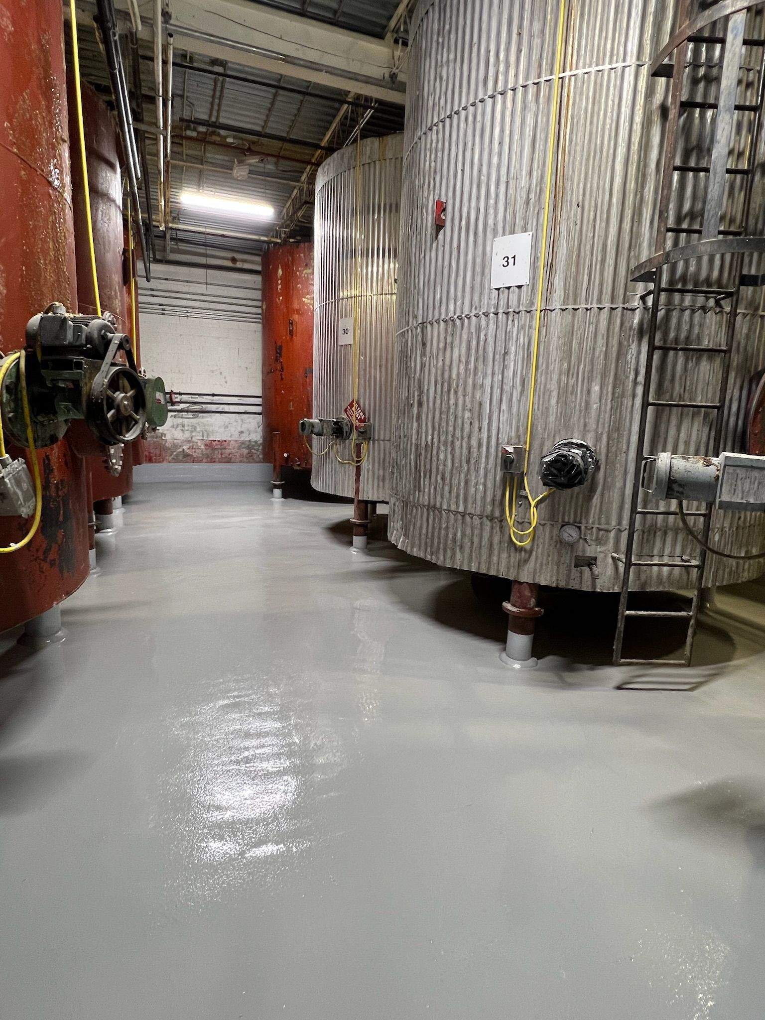 A row of large tanks are lined up in a warehouse.