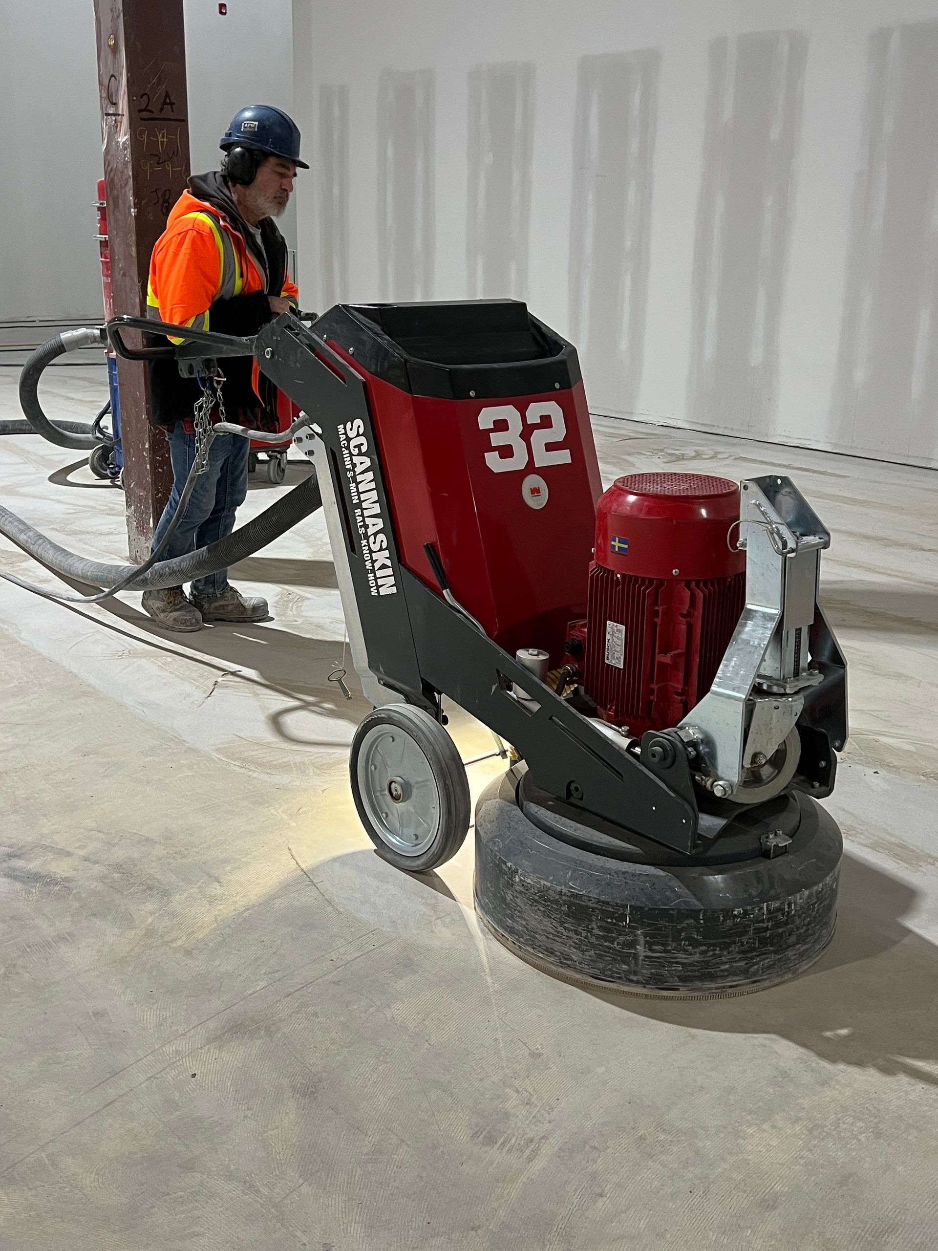 A man is using a machine to grind a concrete floor.