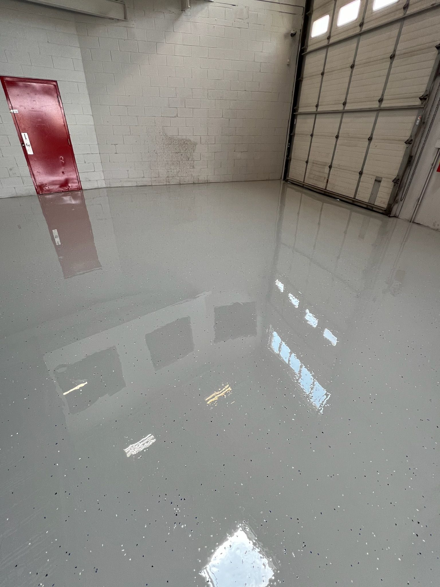 A garage with a gray floor and a red door
