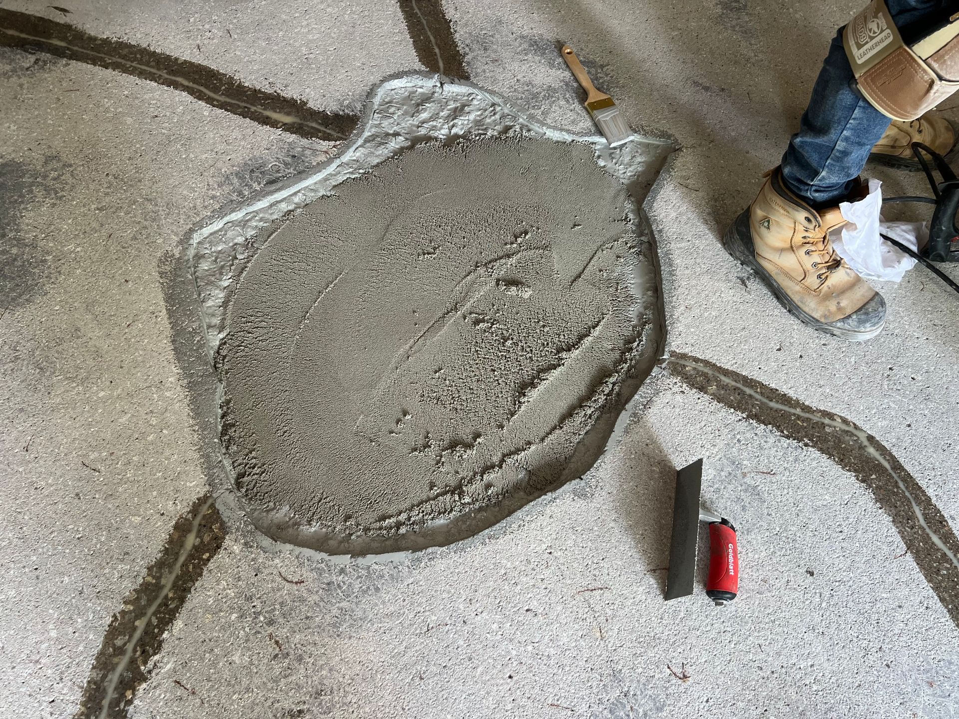 A person is pouring concrete into a hole in the floor.