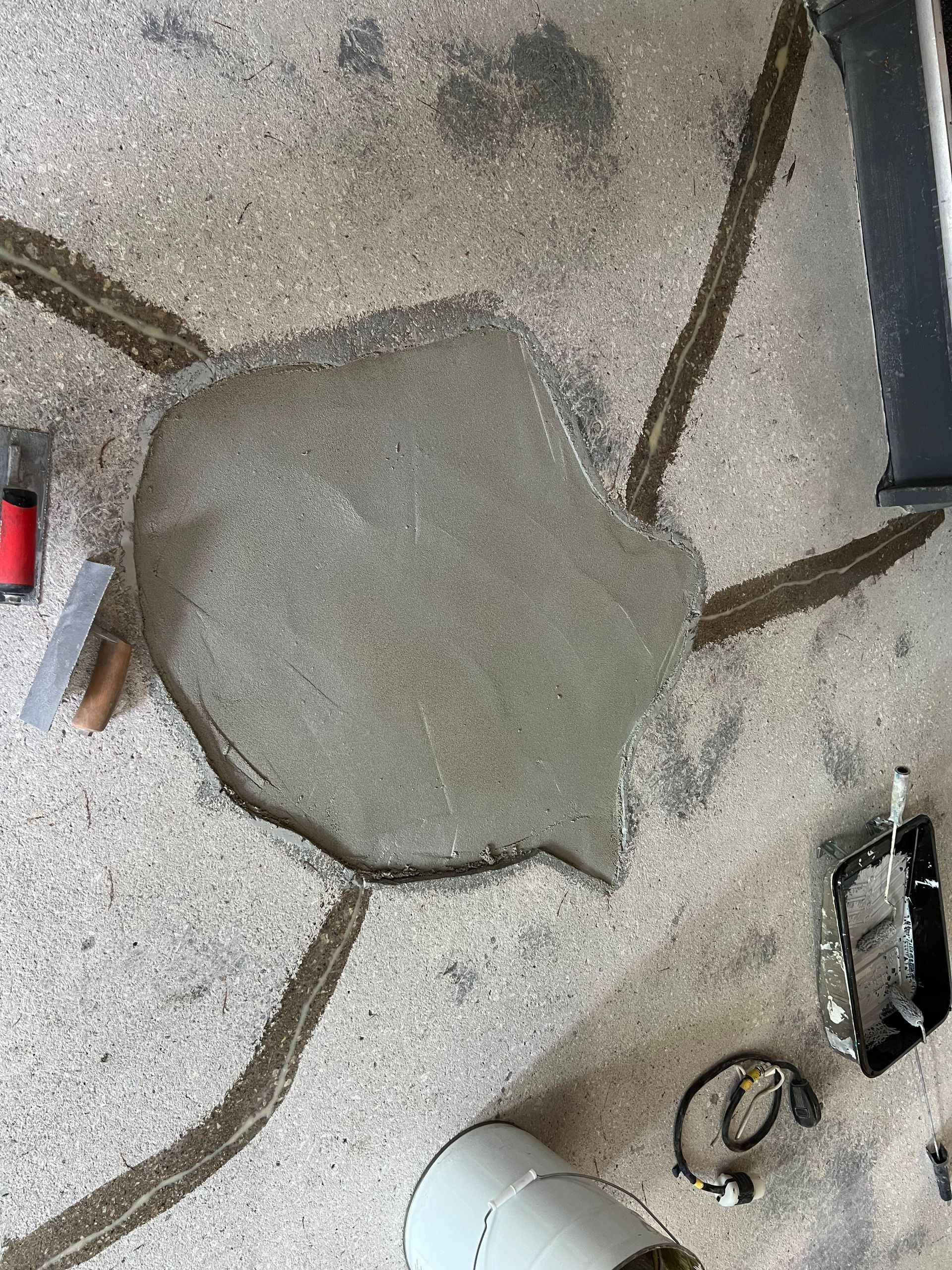 A piece of concrete is sitting on the ground next to tools.