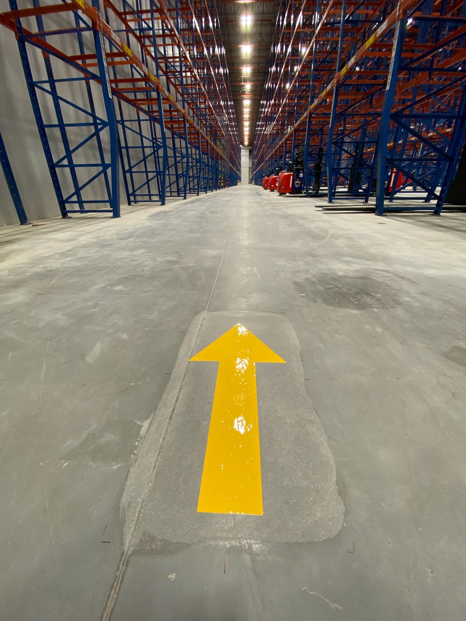A yellow arrow is painted on the floor of a warehouse.