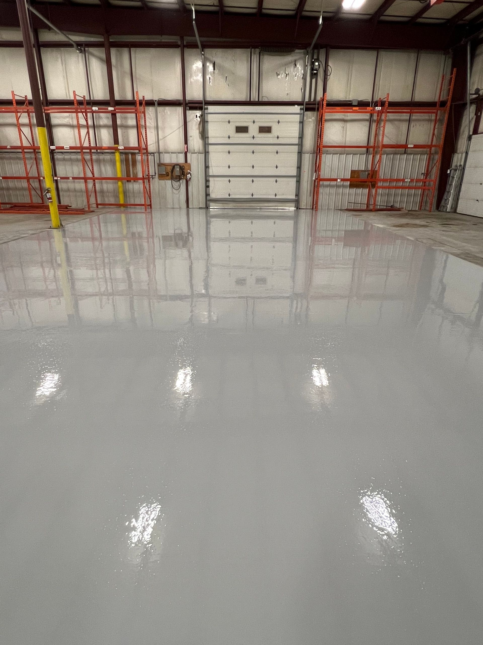 A large warehouse with a concrete floor and a garage door.