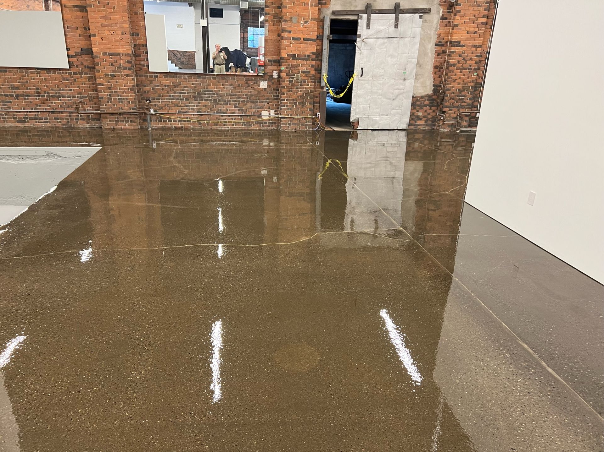 A flooded room with a brick wall and a white door