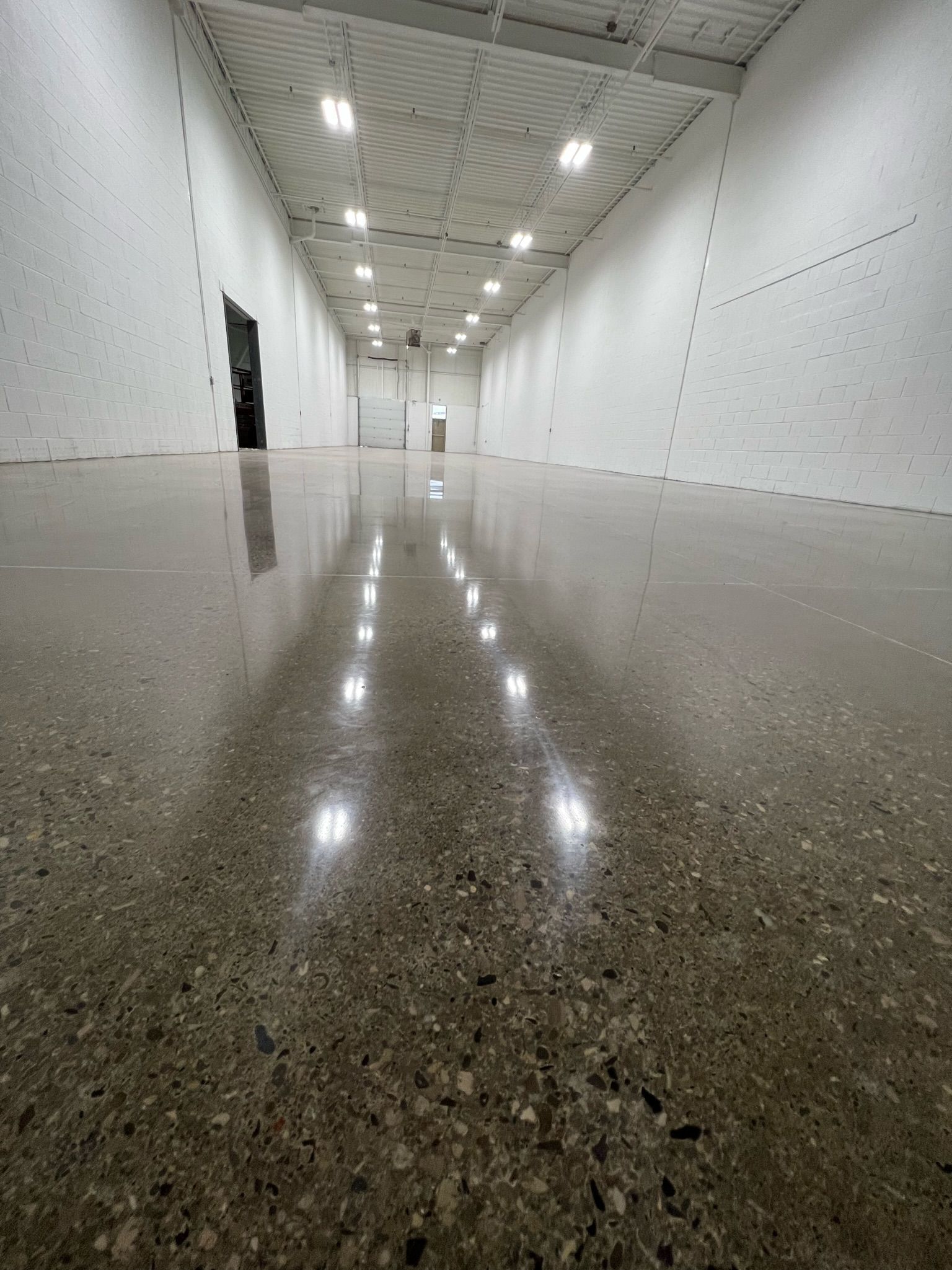 A large empty warehouse with a shiny concrete floor and white walls.