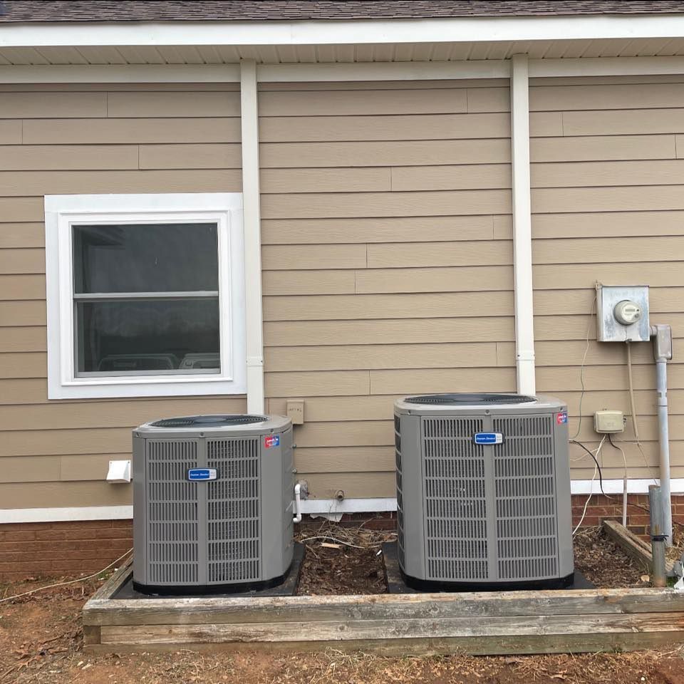 Two air conditioners are sitting on the side of a house.