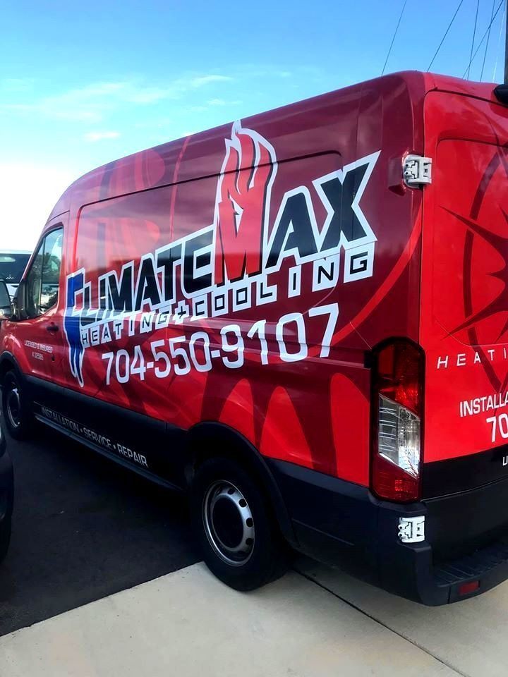A red climate max van is parked on the side of the road.