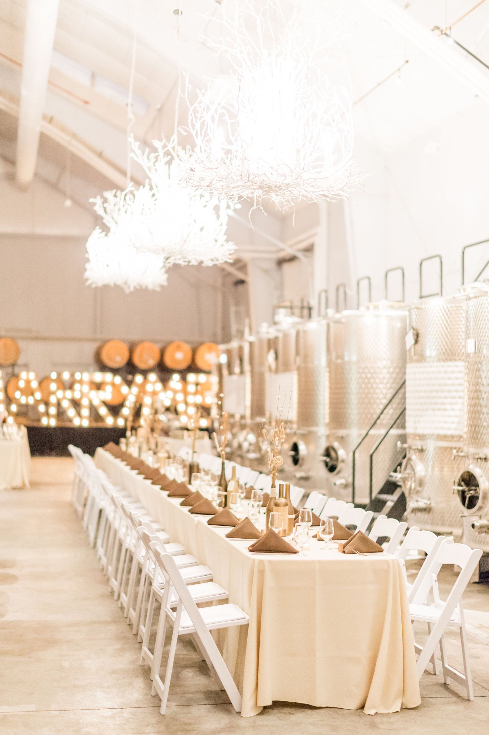 A long table and chairs in a room with barrels in the background.