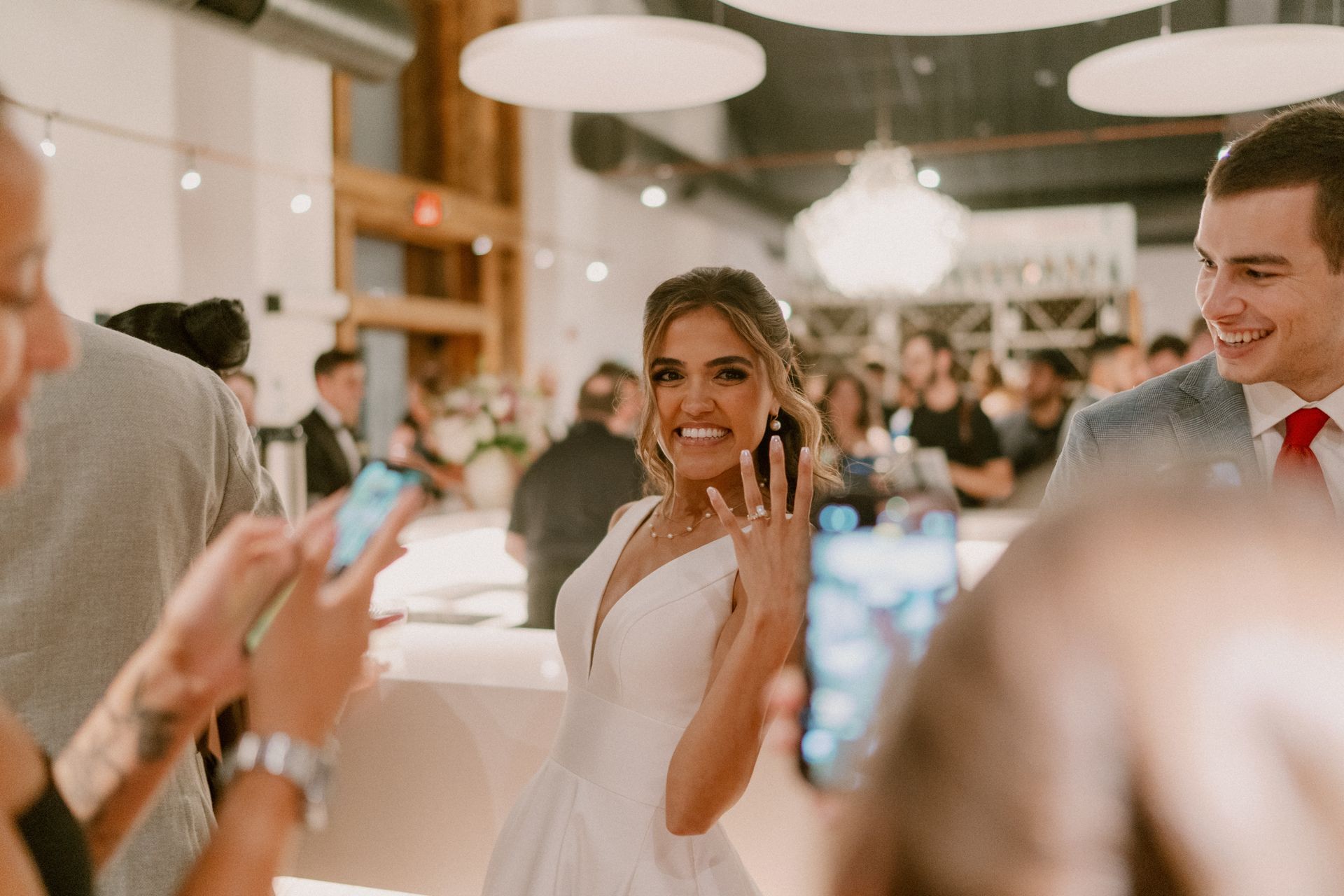 A bride is holding a small dog in her arms in a vineyard.