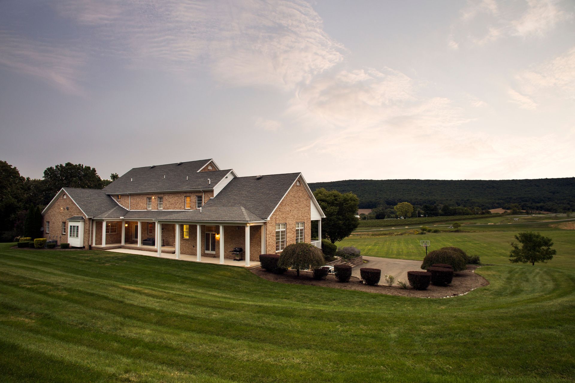 A large house is sitting on top of a lush green field.