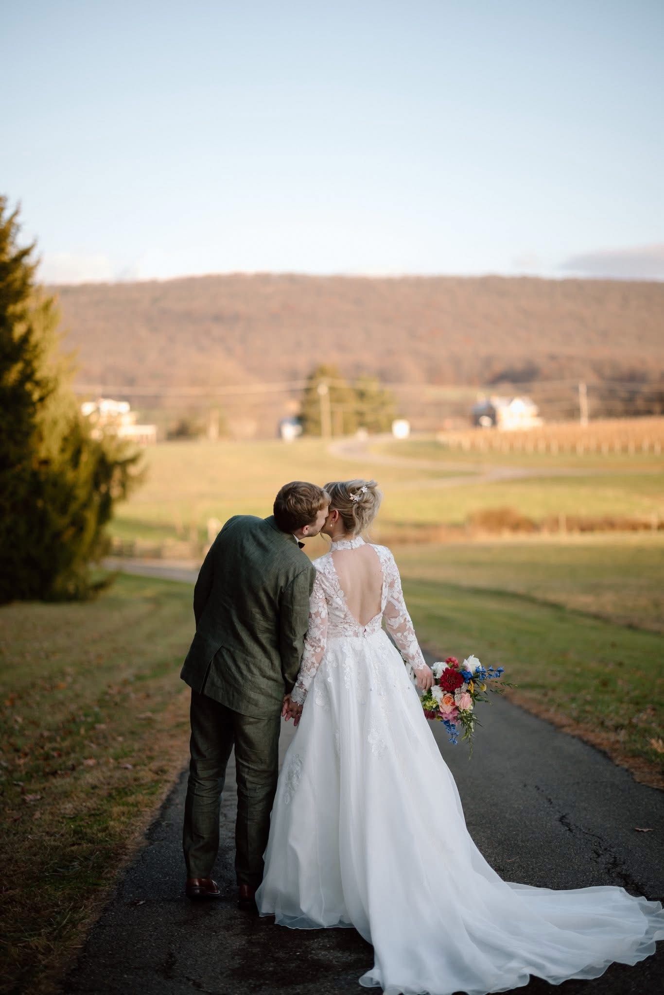 Long dining table set for a formal event in a winery, with wine barrels in the background and floral centerpieces.