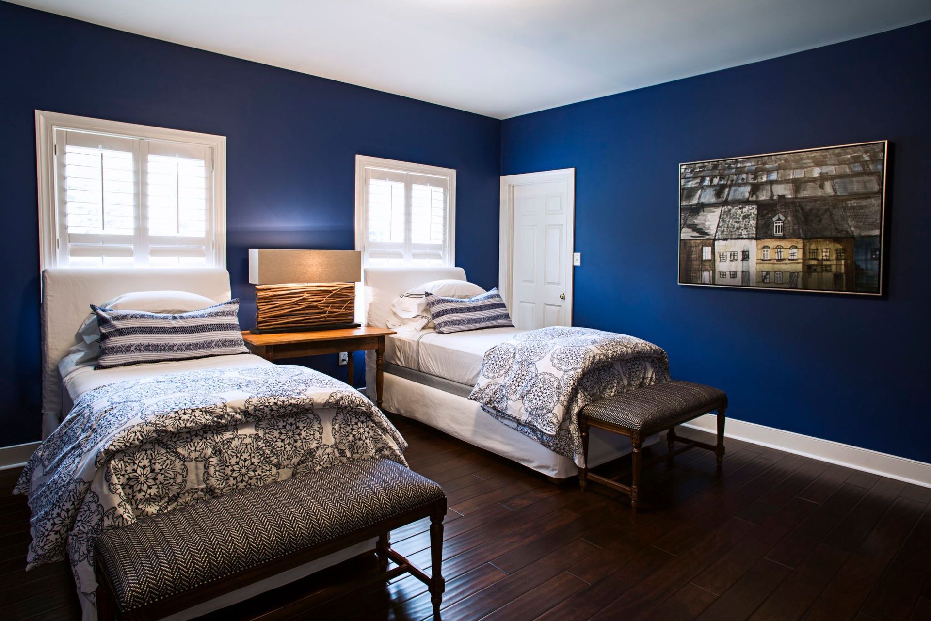 A bedroom with two twin beds and a painting on the wall.