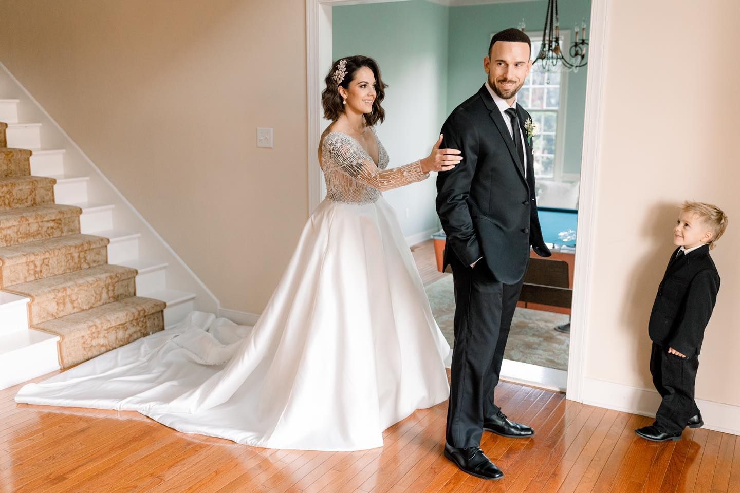 A bride and groom are standing next to a boy in a suit.