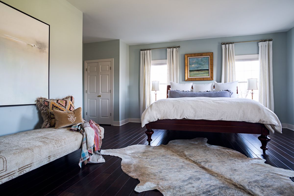 A bedroom with a large bed and a cowhide rug on the floor.