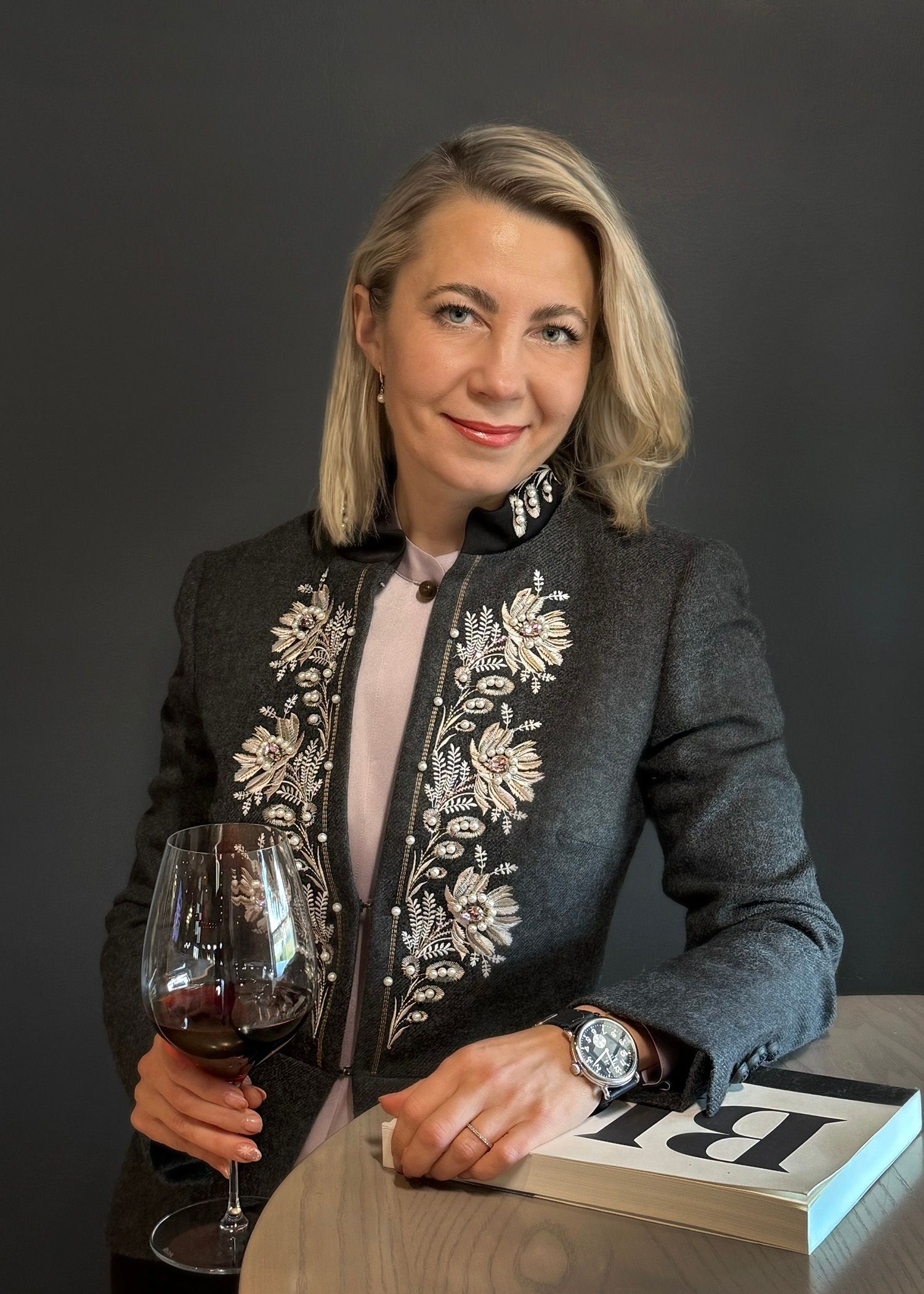 A woman is holding a glass of wine and a book.