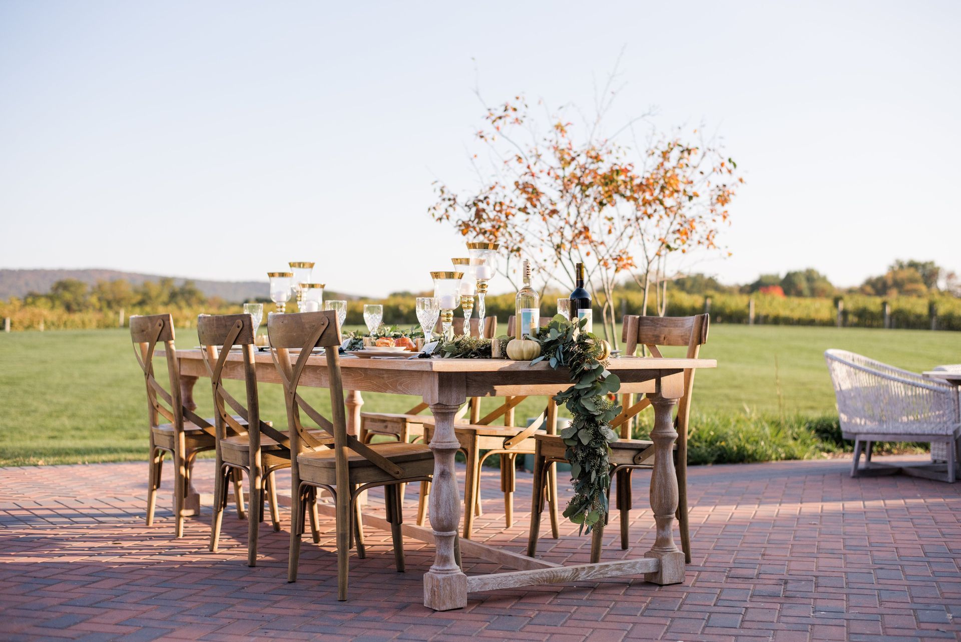 A wooden table and chairs are sitting on a brick patio.