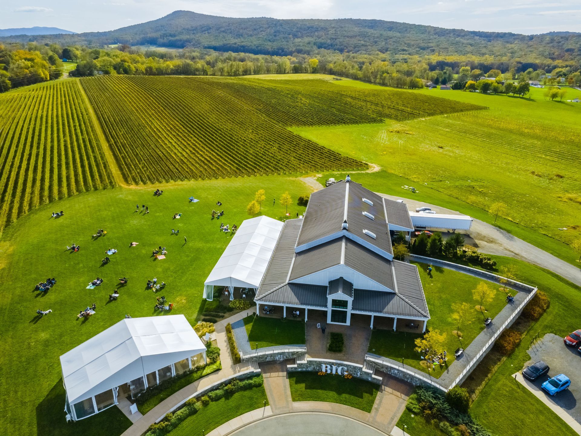 An aerial view of a large building in the middle of a lush green field.