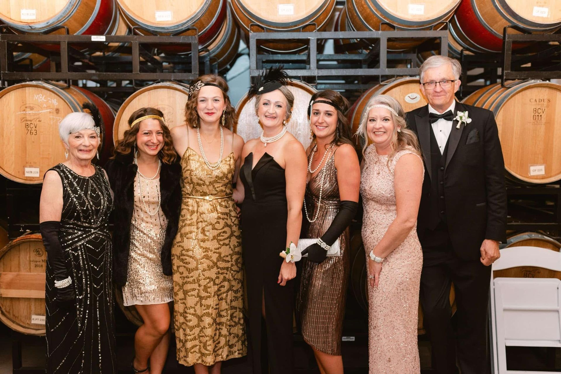 A group of people are posing for a picture in front of wine barrels.