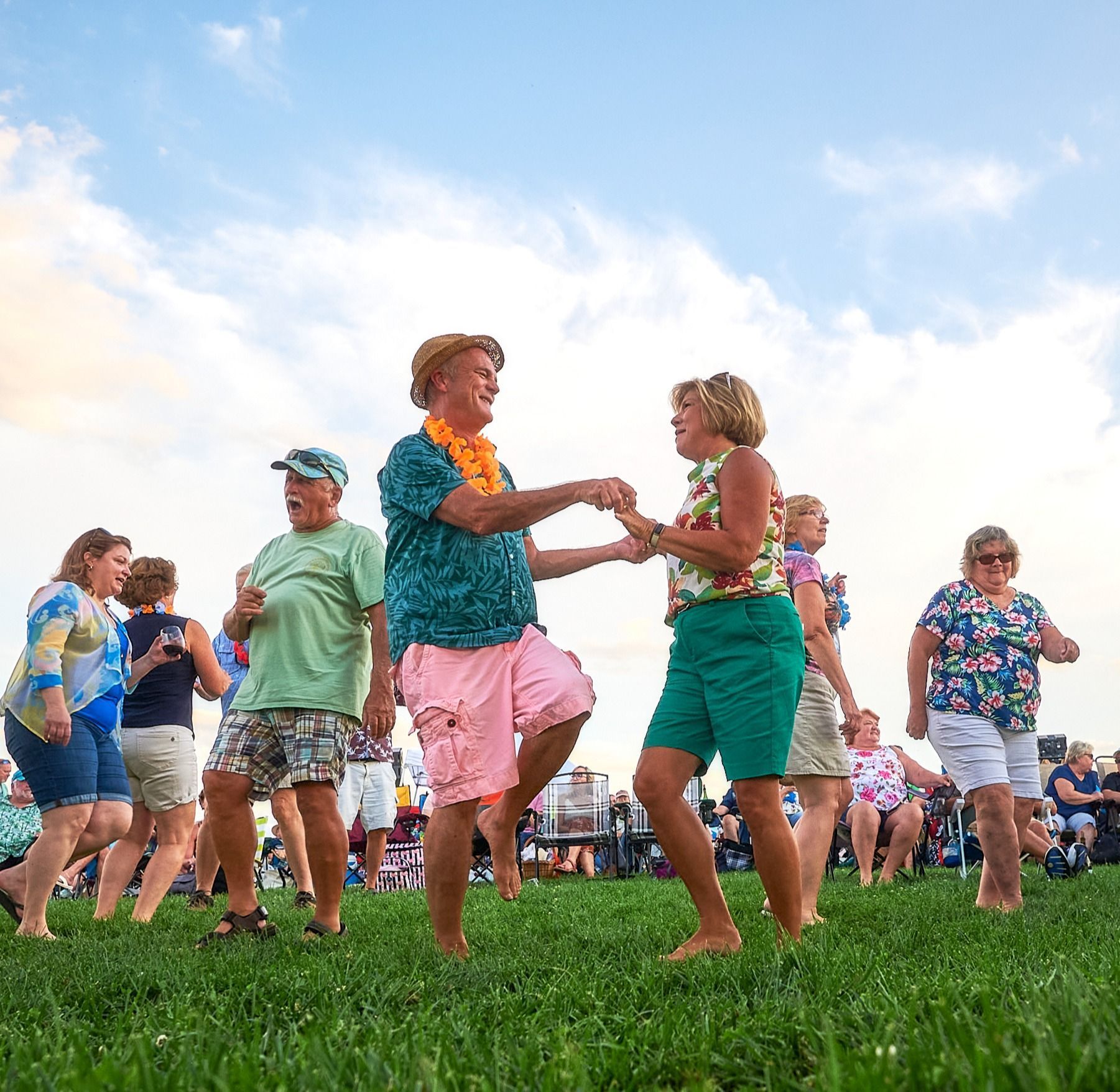A group of people are dancing in a grassy field.