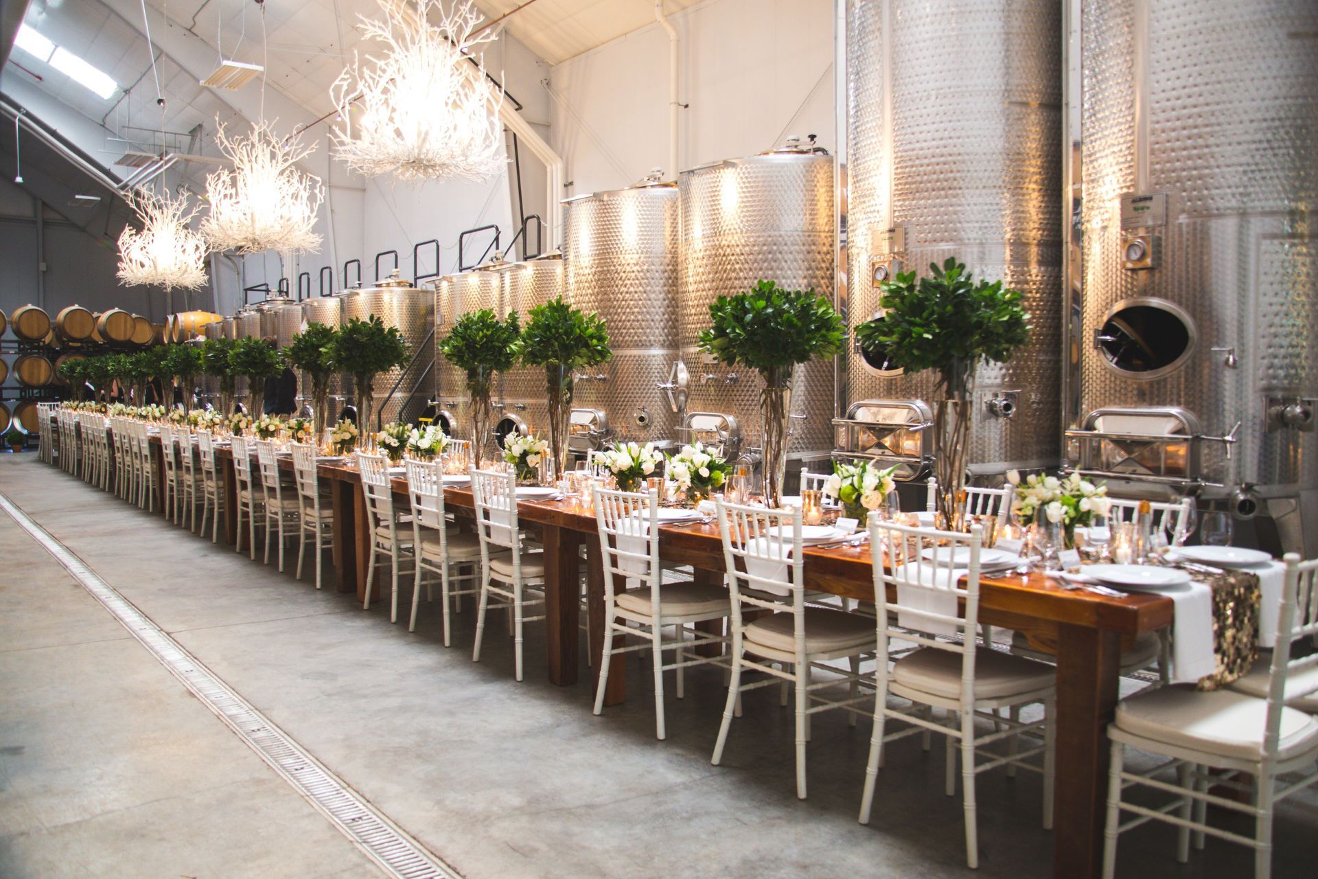 A long table and chairs are lined up in a warehouse.