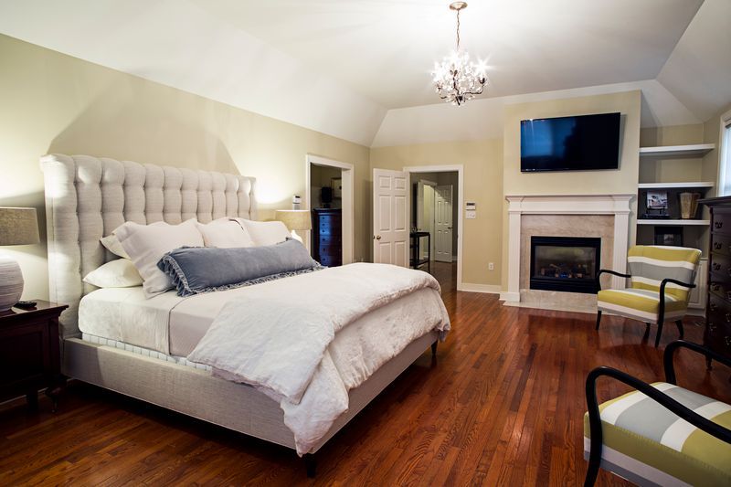 A bedroom with a large bed , fireplace and television.
