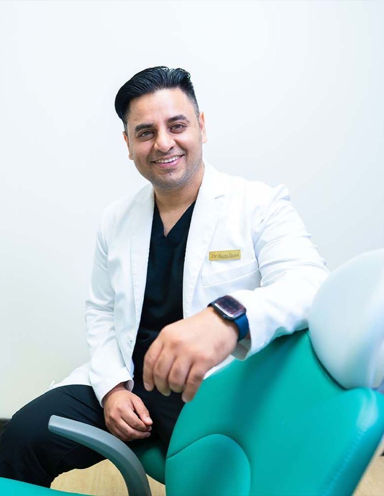 A woman is smiling while sitting in a dental chair.