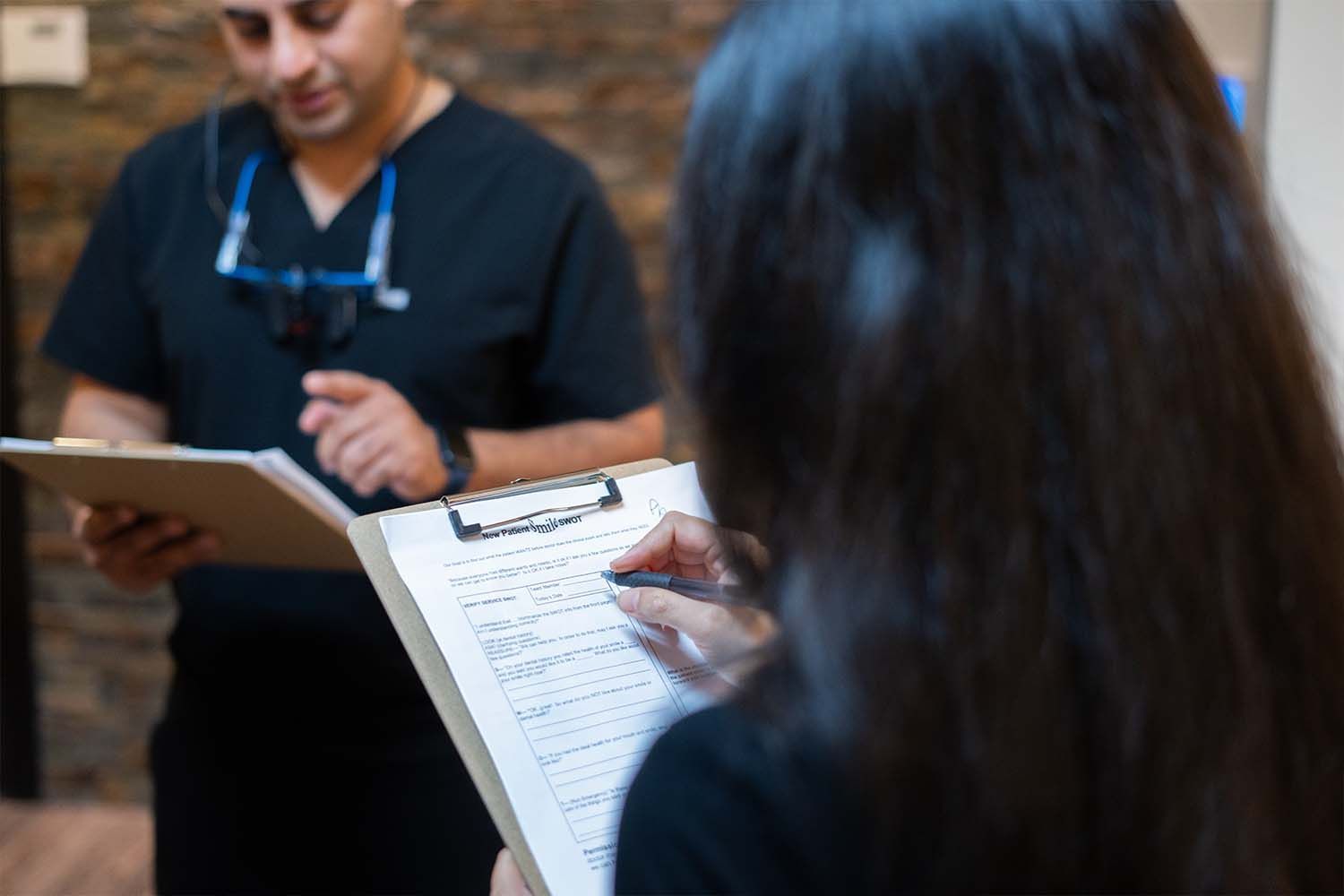 A woman is sitting in a dental chair with her hand on her face.