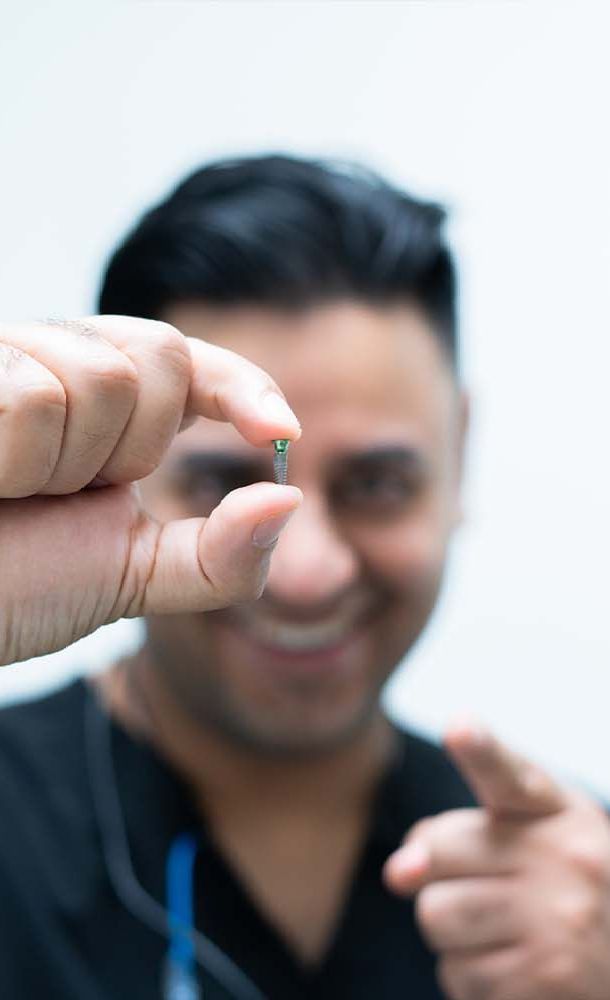 A man is smiling while looking at his teeth in a mirror.